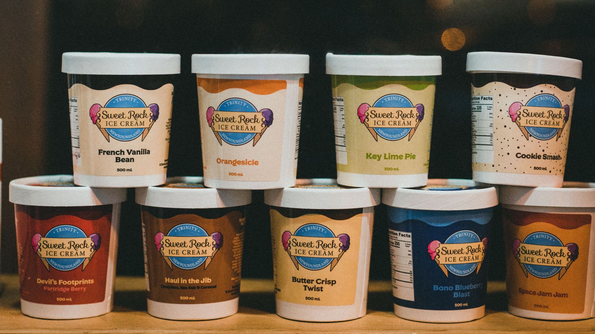 Various Sweet Rock ice cream flavors in branded containers displayed in a stack.