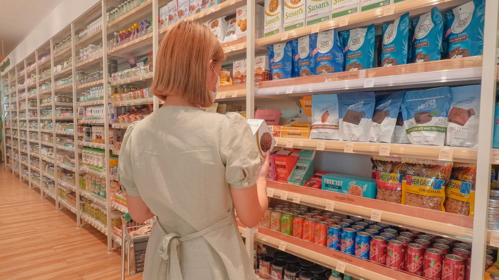 a woman in a white dress is looking at a shelf of food