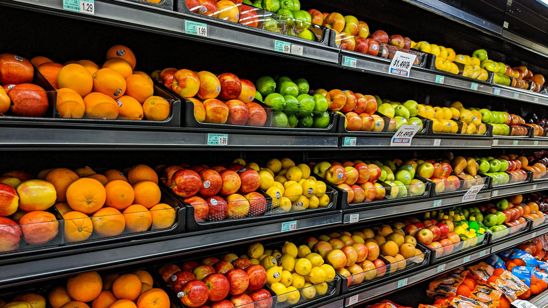 Shelves of fresh oranges, apples, lemons, and limes in a grocery store