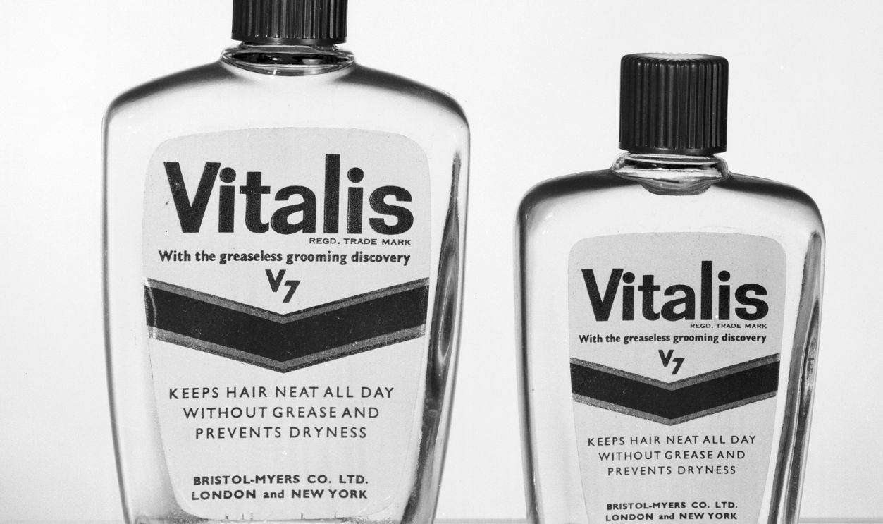 Getty Images - 3141640 - Two bottles of Vitalis hair tonic by Bristol-Myers Co Ltd, for 'greaseless grooming'. Graham & Gillies.