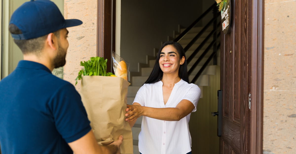 Cheerful woman is receiving a grocery bag from a delivery man in front of her house