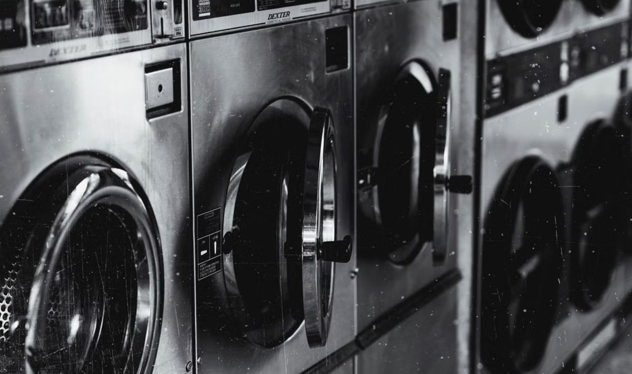 Black and white image of industrial washing machines in a retro style laundry facility
