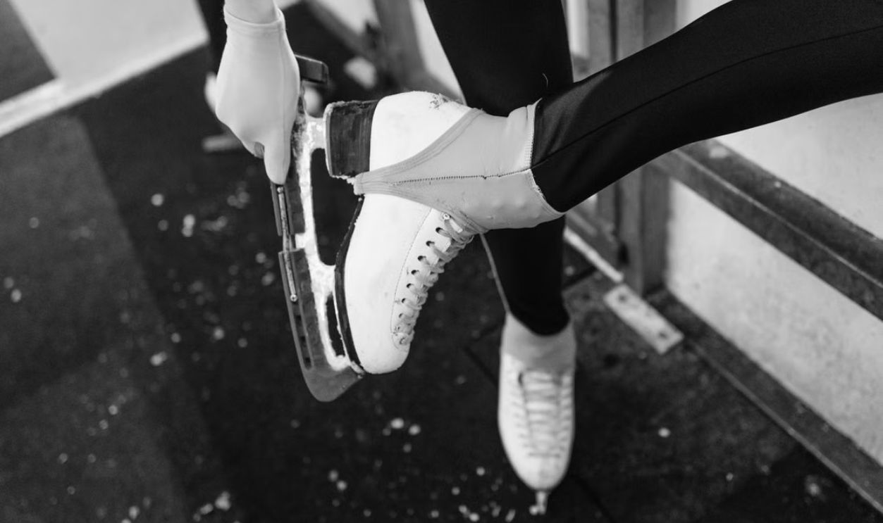 Black and white close-up of a figure skater tying ice skates before practice