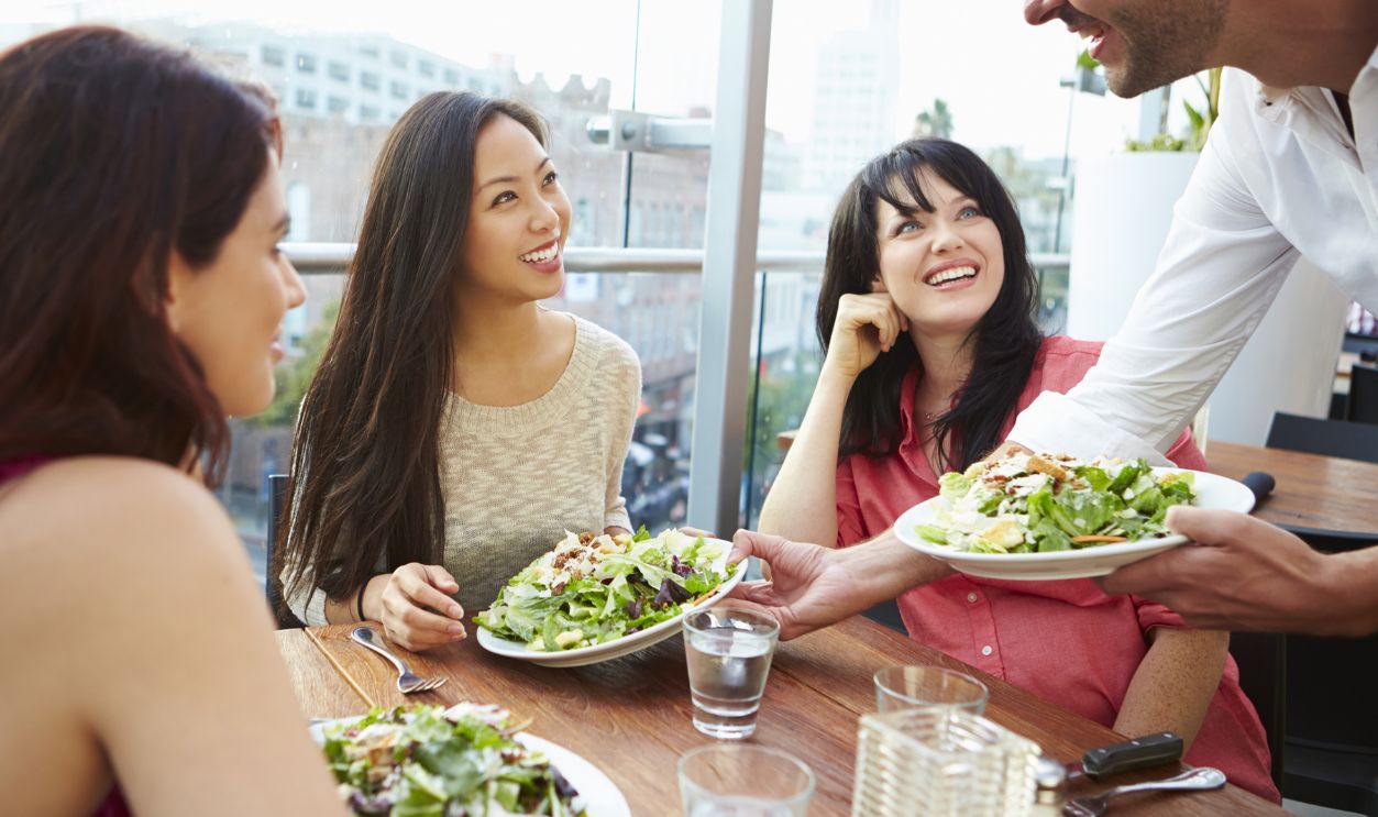 Three Female Friends Enjoying Lunch At Rooftop Restaurant