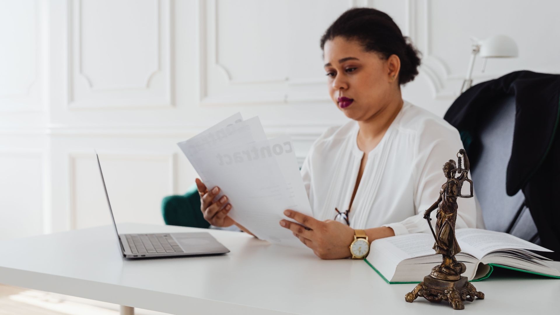 Black woman lawyer reading legal papers at her desk in a modern office.