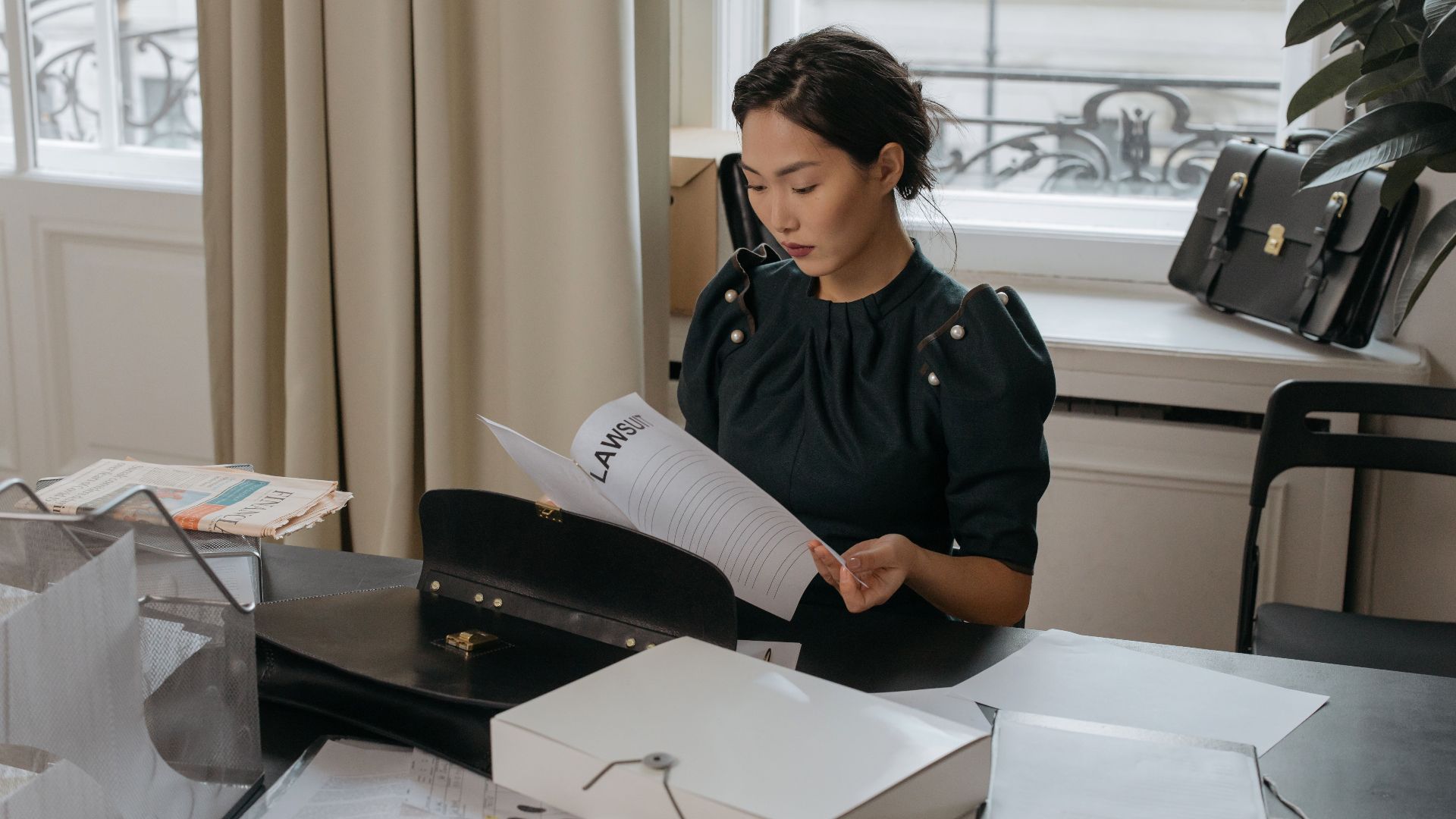 Elegant young woman reading documents in a stylish office setting.