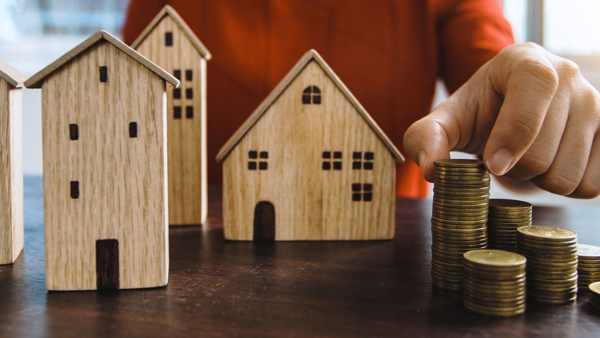Planning investments with stacked coins and model houses on a table.