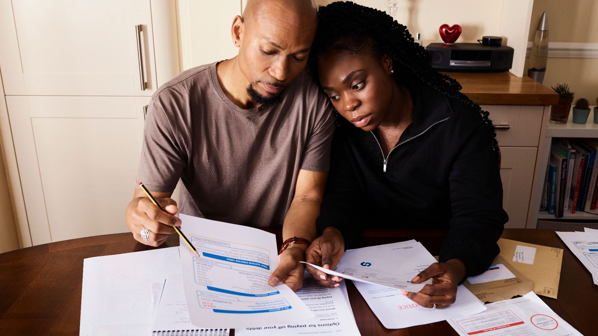 A couple sitting at a table reviewing financial documents, highlighting domestic budgeting.
