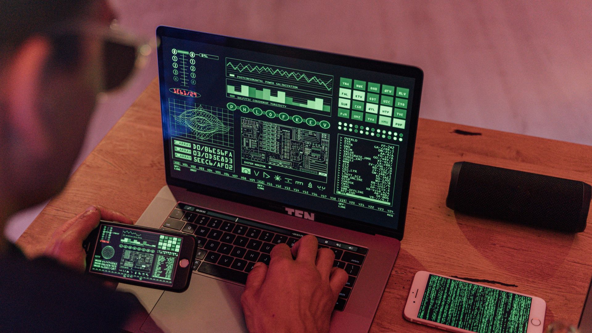 Man working with cybersecurity software on laptop and smartphone.