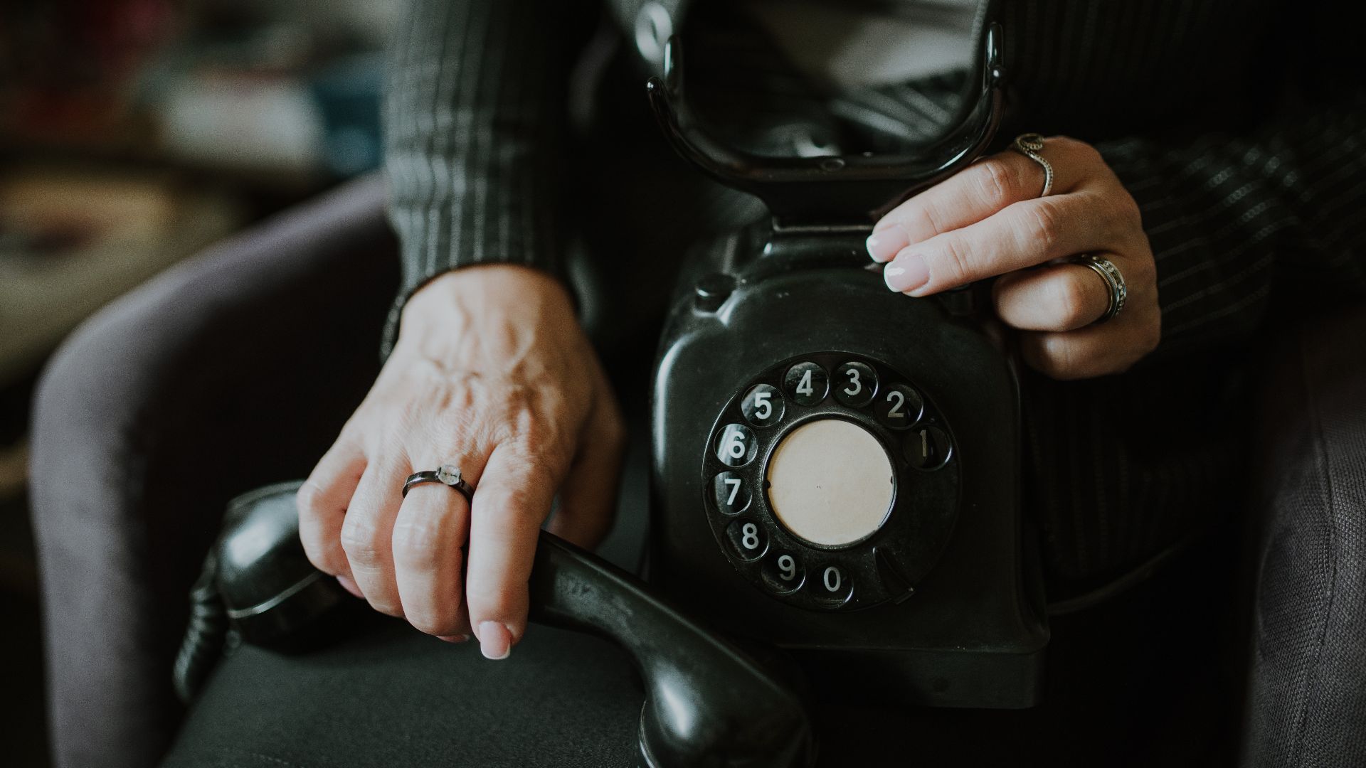 A woman holds a classic rotary phone in a warm, inviting room, highlighting the charm and nostalgia associated with vintage communication devices. The setting feels intimate and personal.