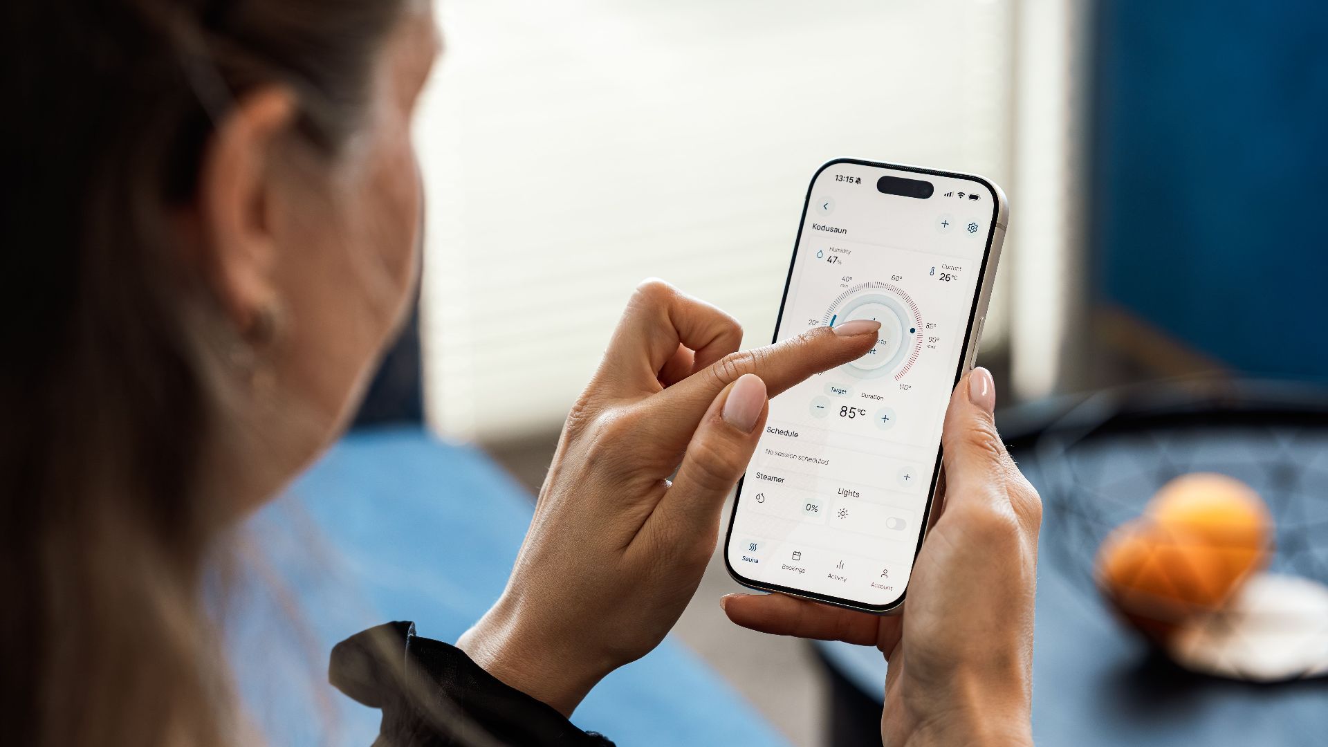 Close-up of a woman using a smartphone app to control sauna settings, indoors.