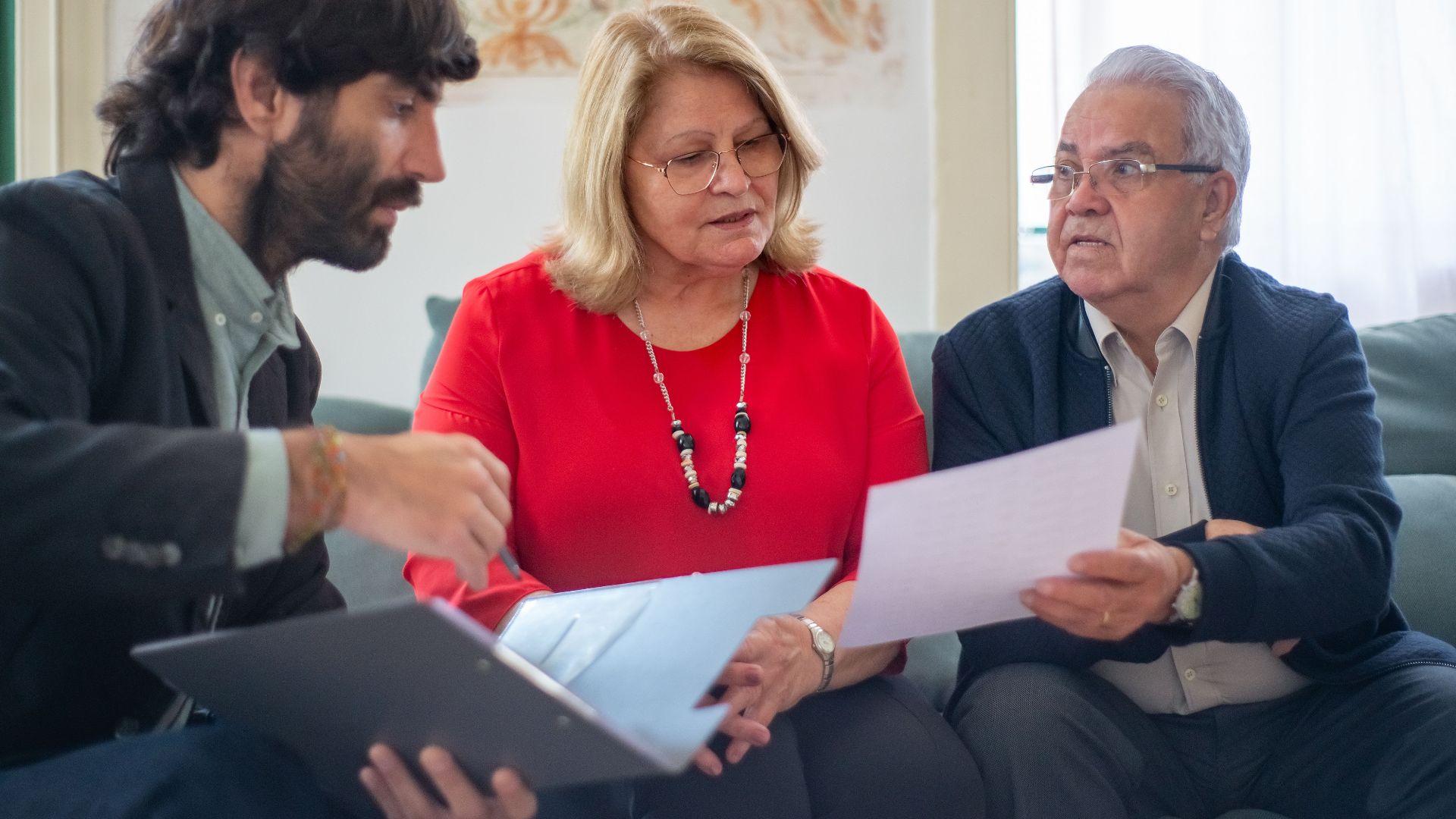 Senior couple consulting with a professional advisor, discussing documents indoors.