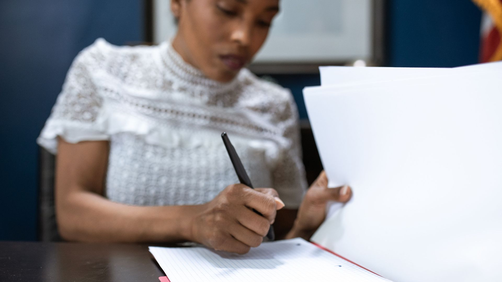 African American woman signing documents in an elegant office setting, showcasing leadership.