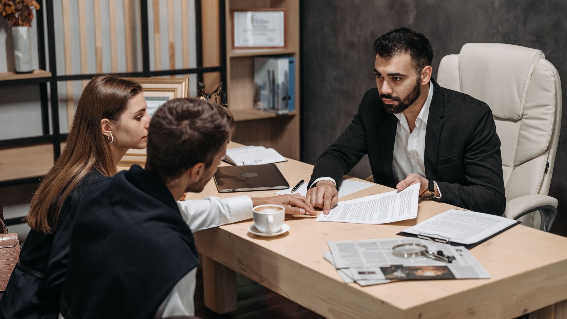 Lawyer discussing legal documents with clients at office desk.