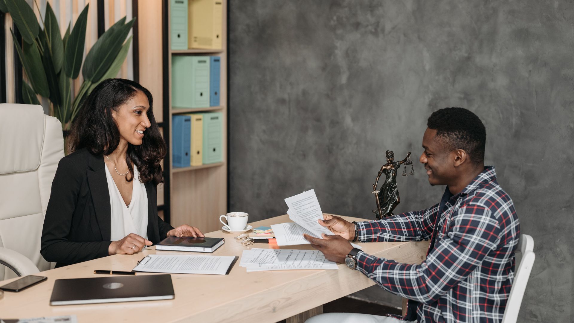 Two professionals having a discussion in a stylish office with paperwork and a laptop.