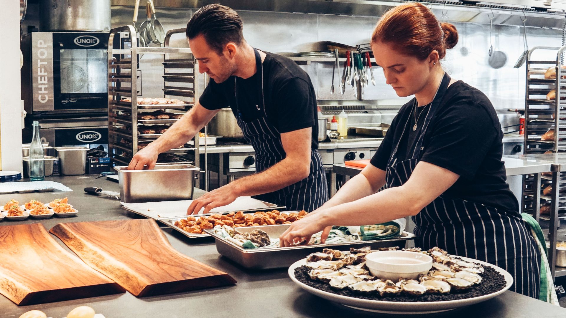 Two chefs working together in a professional kitchen, preparing gourmet dishes with precision.