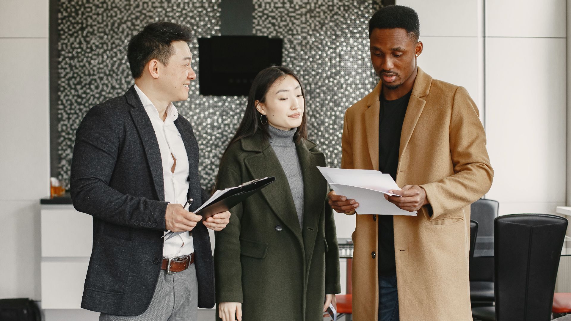 Three colleagues reviewing business documents in a modern office setting.