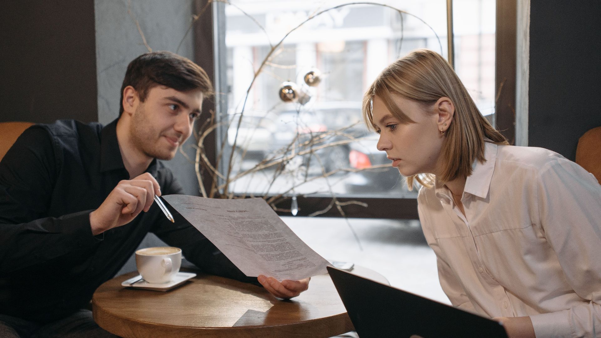 Engaged colleagues discussing documents over coffee in a cozy cafe setting.