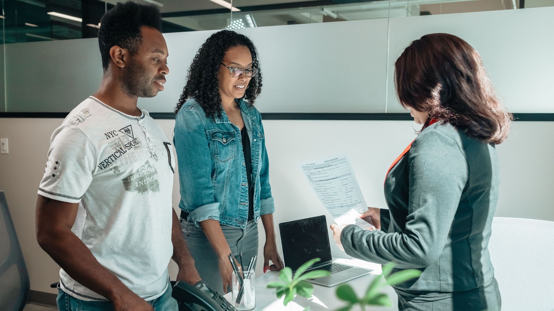 A diverse group in a business meeting discussing documents in a modern office setting.