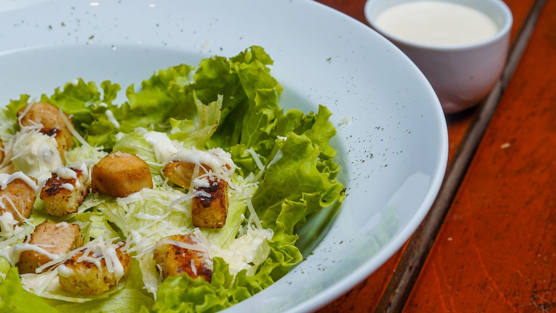 Fresh Caesar salad with crisp lettuce, croutons, and cheese in a white bowl.