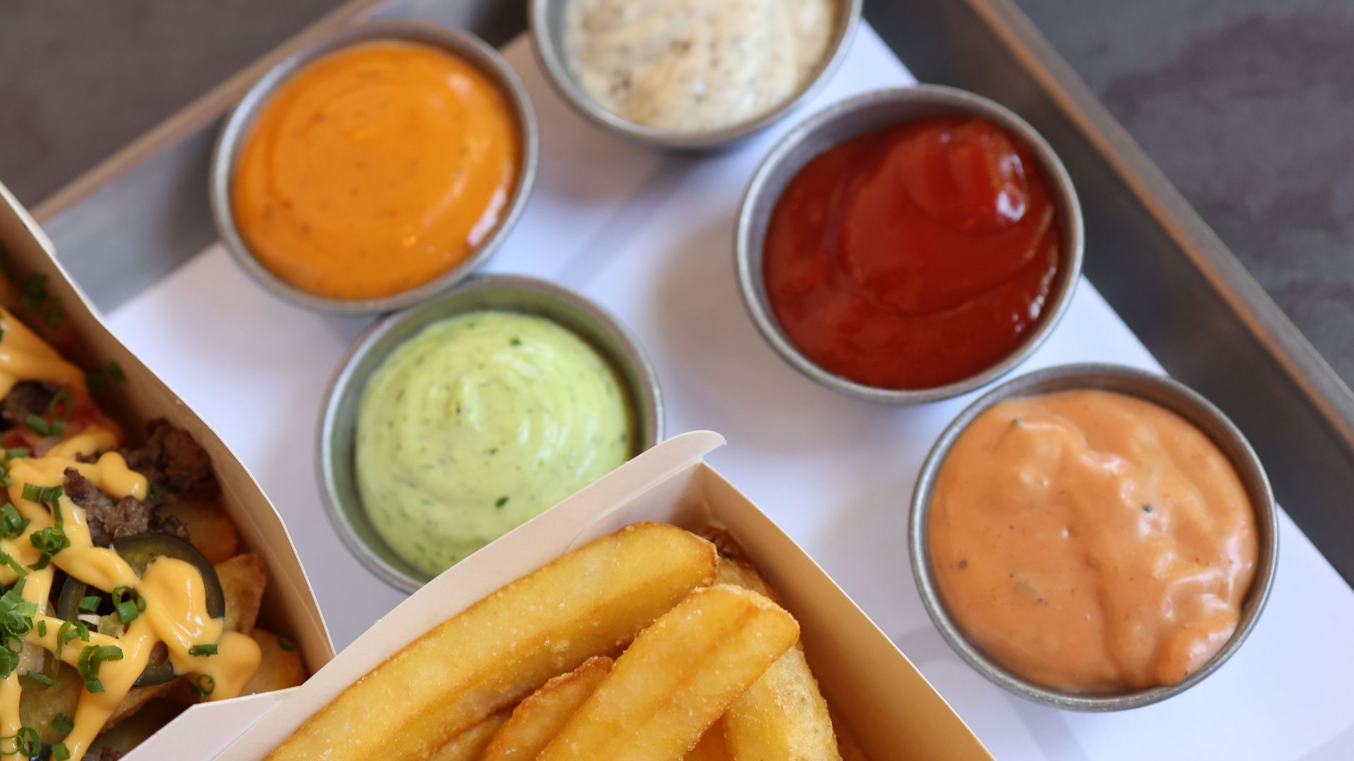 Golden French fries served with a variety of four flavorful dipping sauces, ideal for a tasty snack.