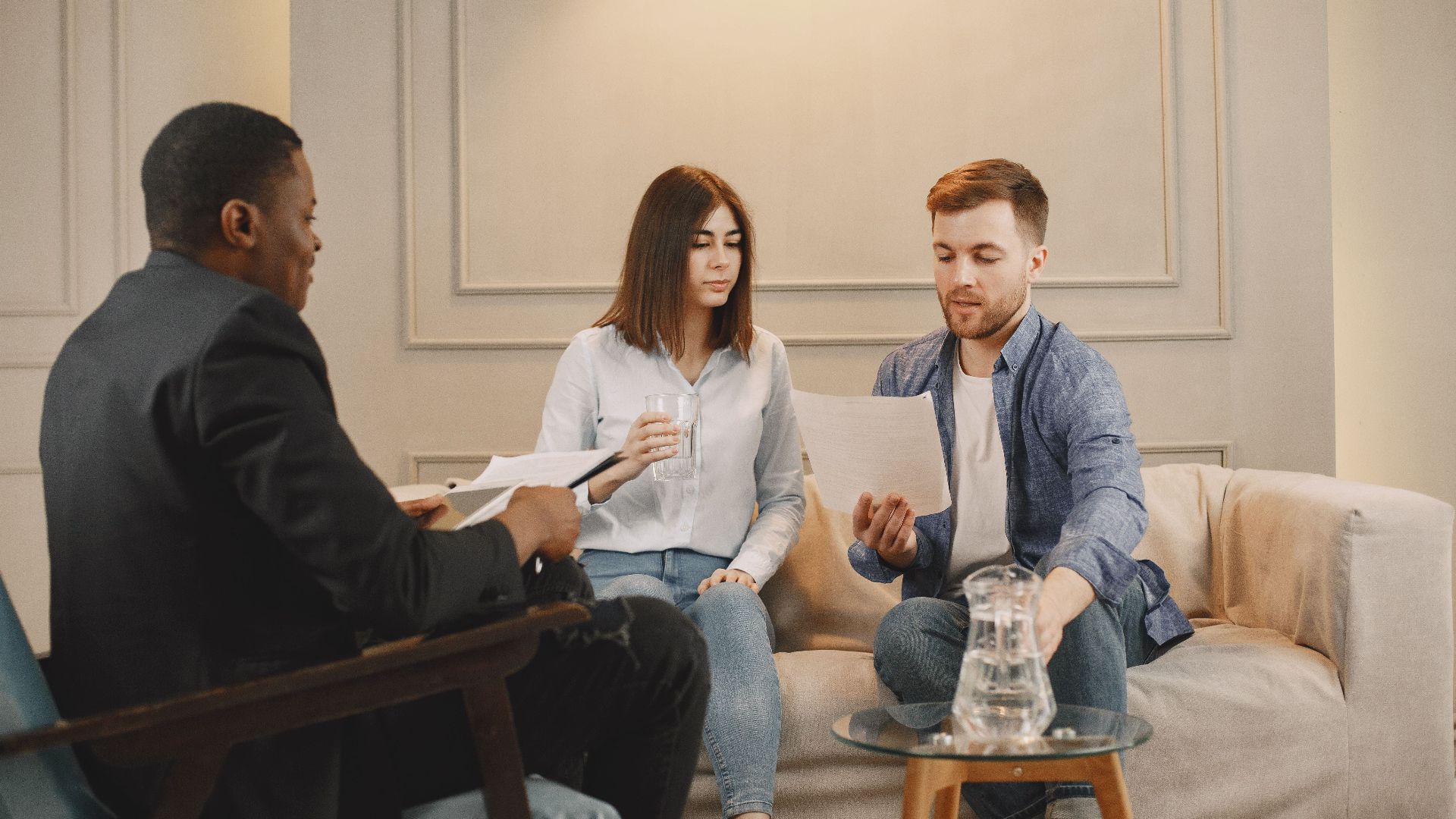 Therapist counseling couple with documents in contemporary office setting.