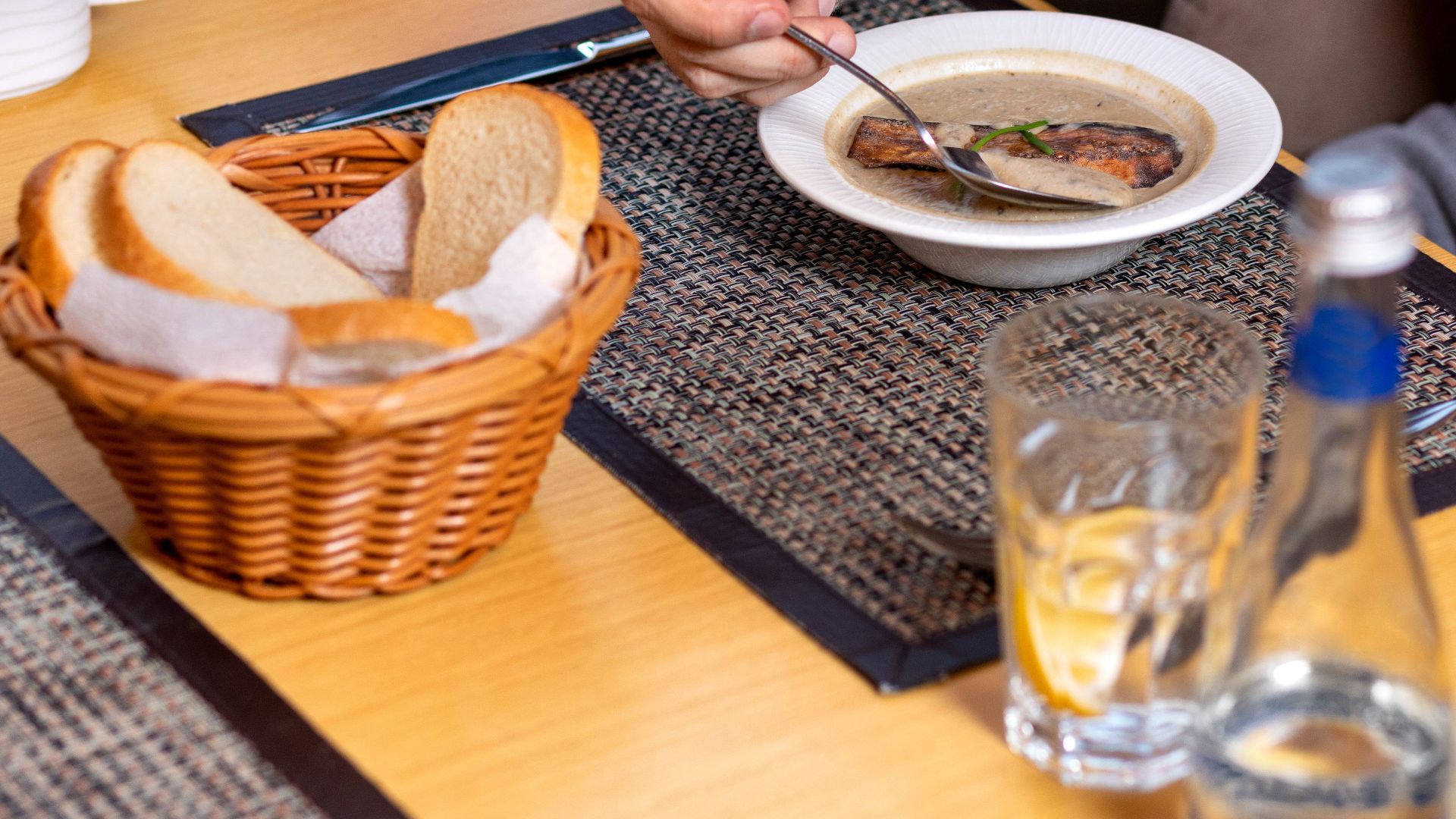 A person enjoying soup with bread in a cozy indoor restaurant setting.