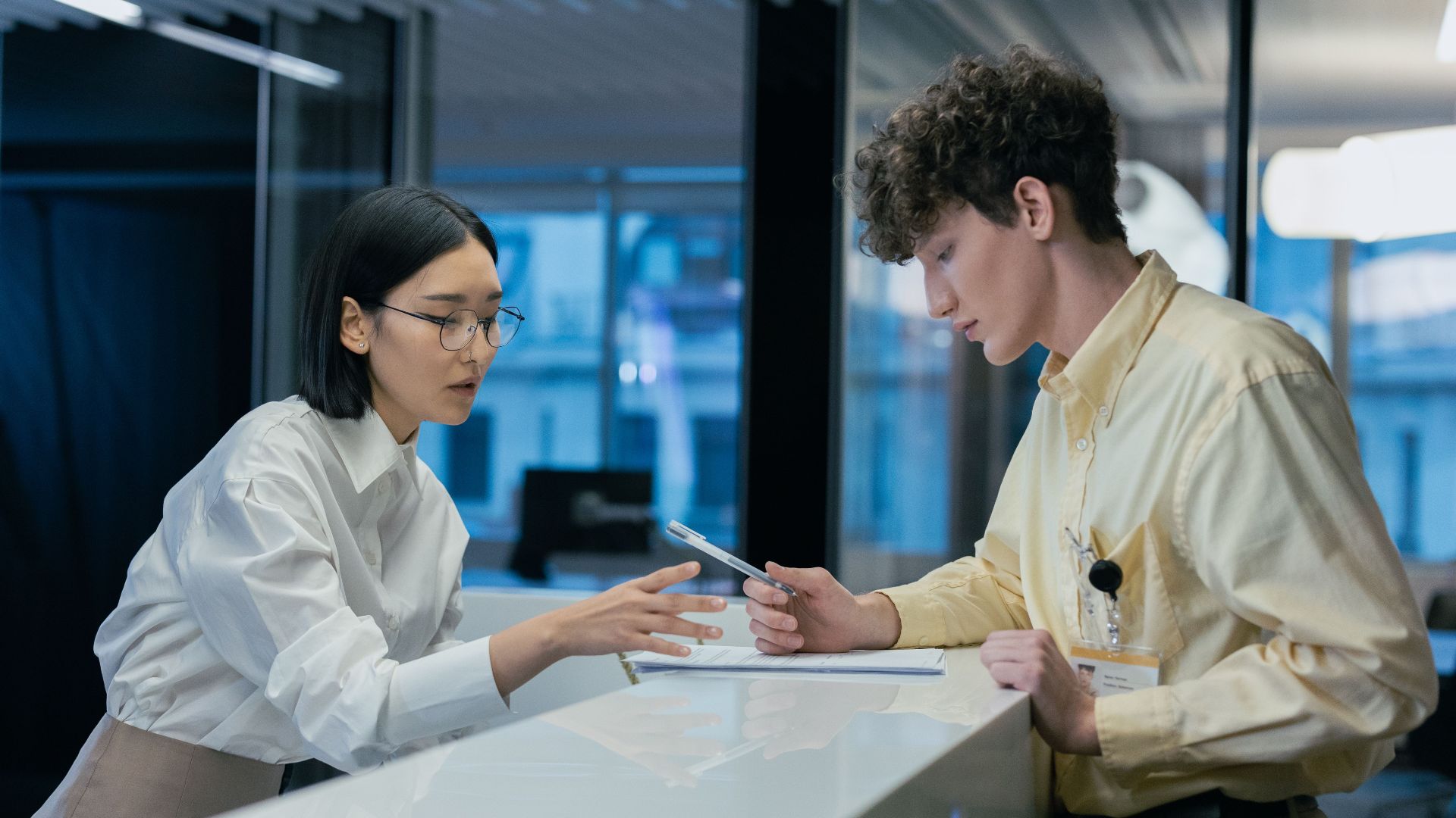 Two professionals discussing at a modern reception, highlighting teamwork and customer service.