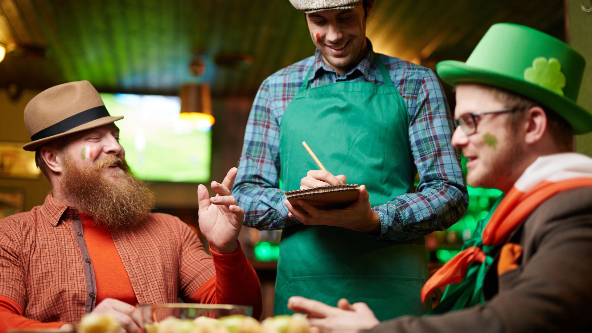 Men celebrating St. Patrick's Day with a waiter taking orders in a pub.