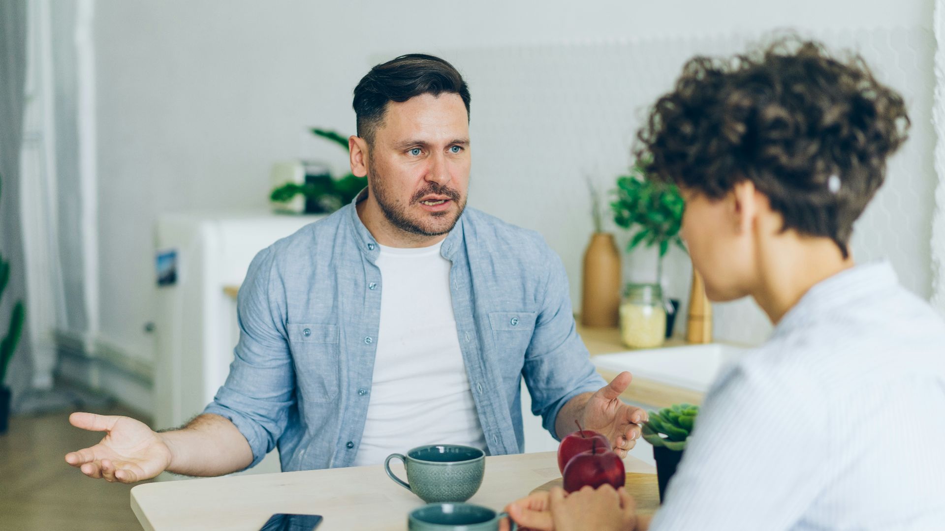 a man sitting at a table talking to a woman