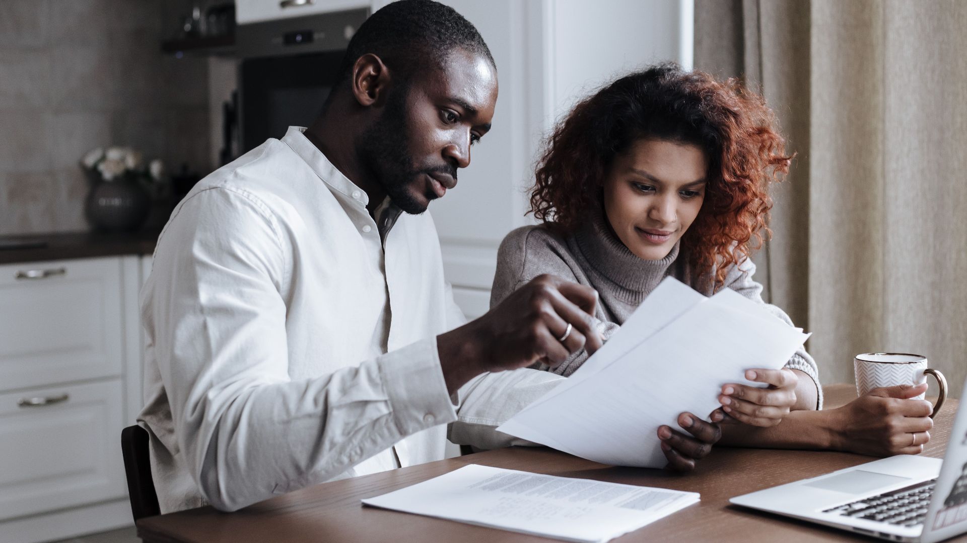 Couple working together on documents at home interior using a laptop.