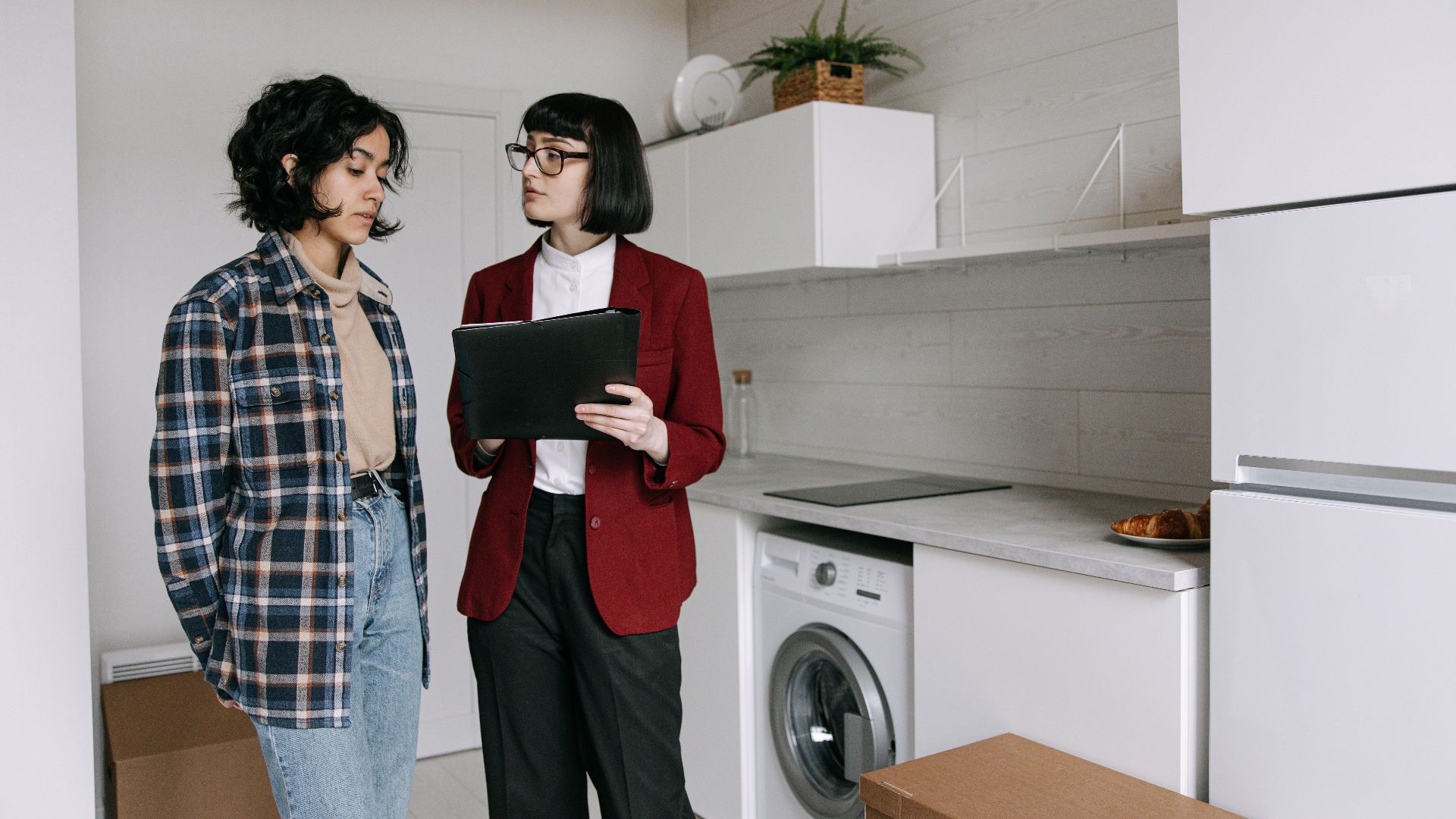 Real estate agent discussing home details with a client in a modern kitchen setting.