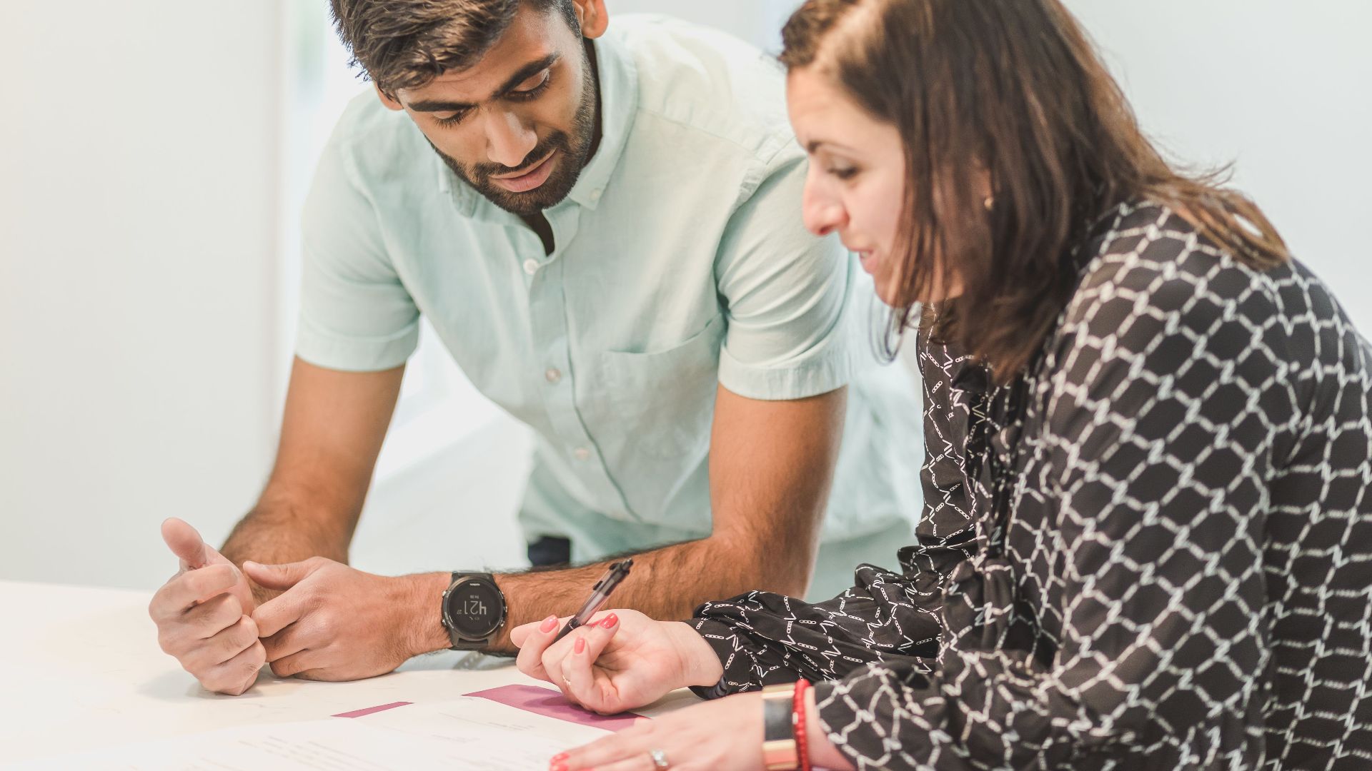 A real estate agent assists a client with home buying paperwork indoors.