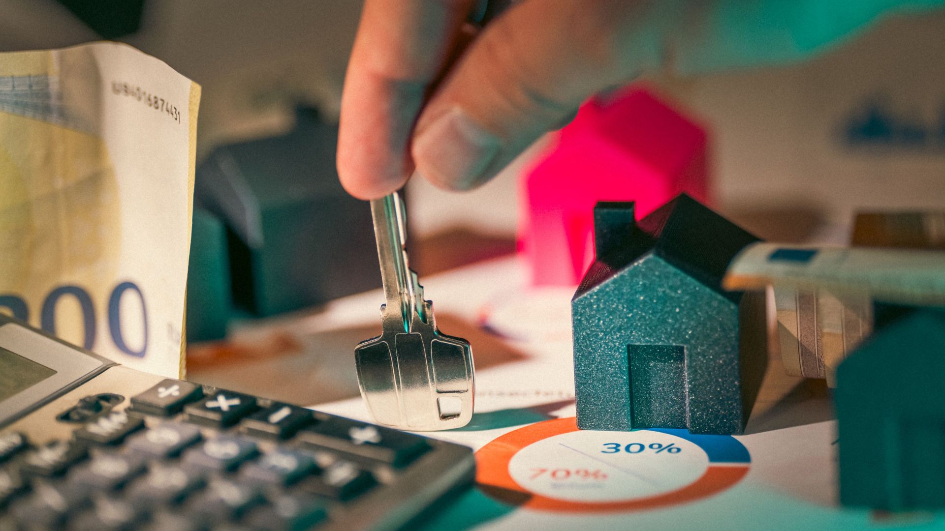 A close-up of real estate financial planning with keys, calculator, and money.