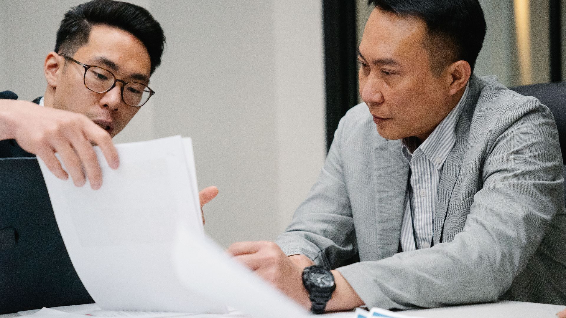Two professional men engaged in a focused discussion in a contemporary office environment.