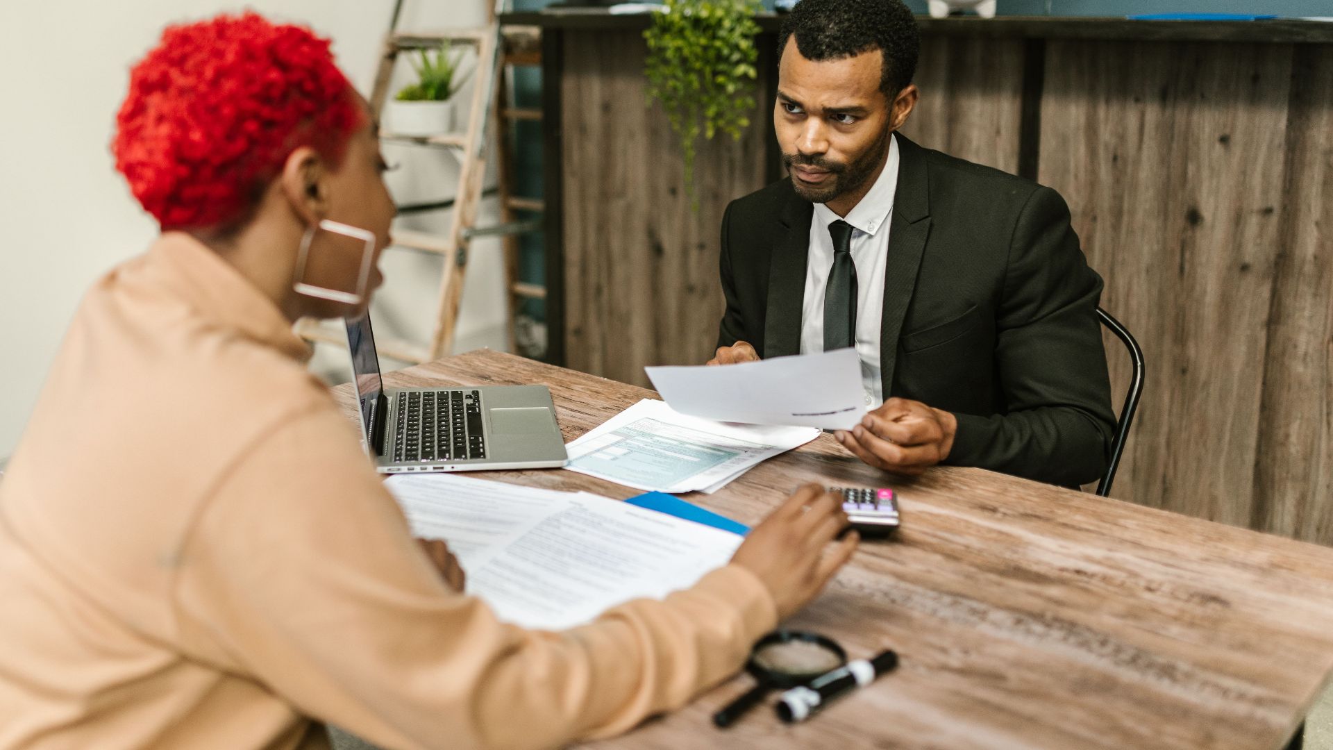 A discussion between two professionals focusing on financial documents in a modern office setting.