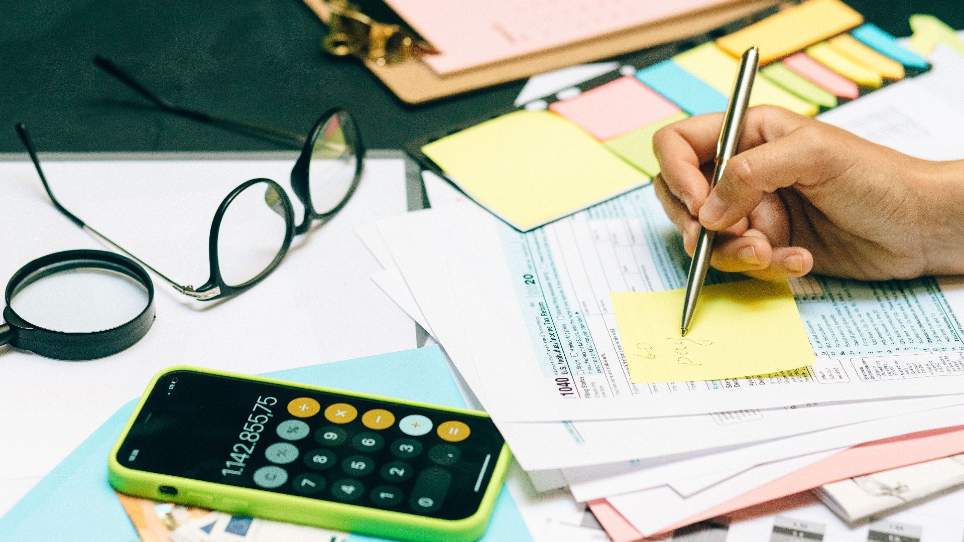 Close-up of an office desk with a calculator, glasses, and documents for financial planning.