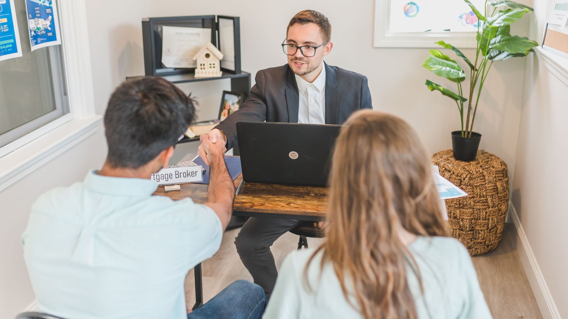 Men and woman discussing mortgage with broker in a modern office setting.