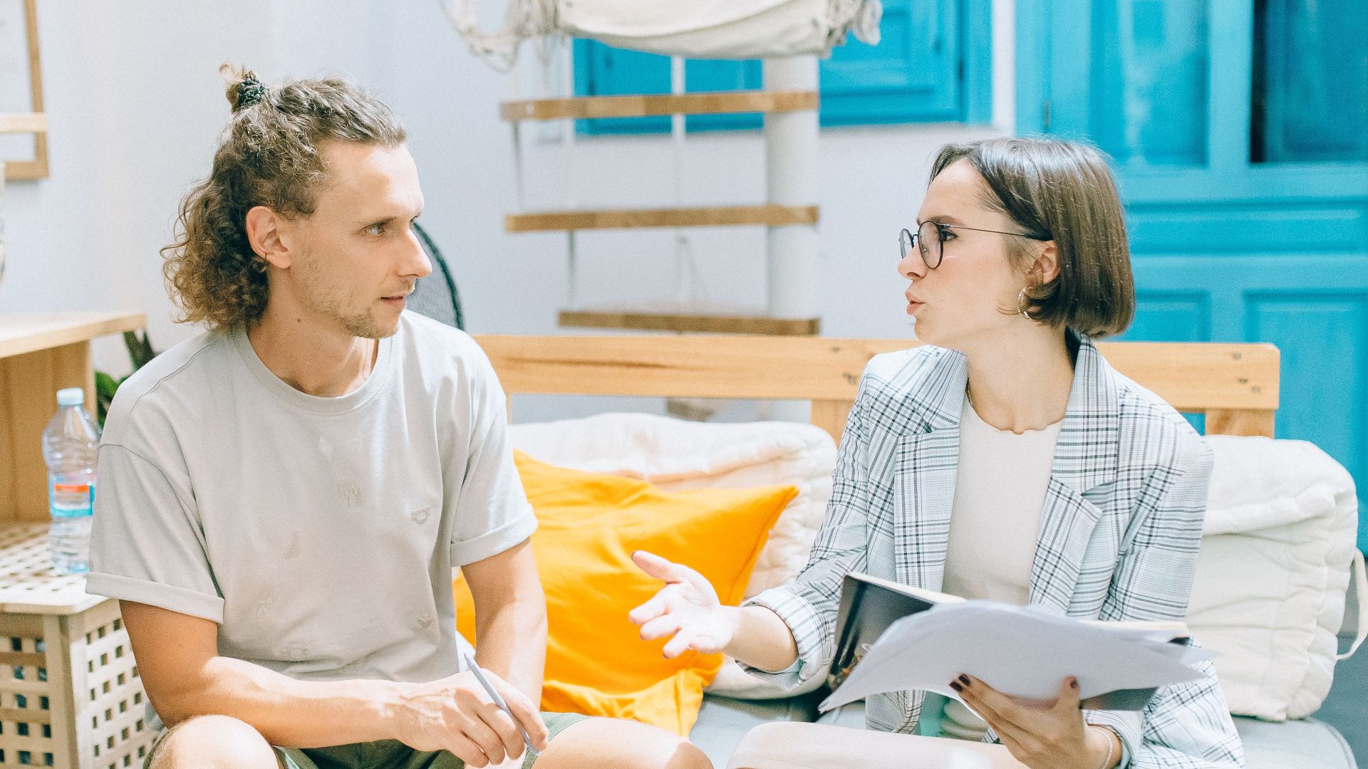 A man and woman discussing work in a stylish, bright living room setting.
