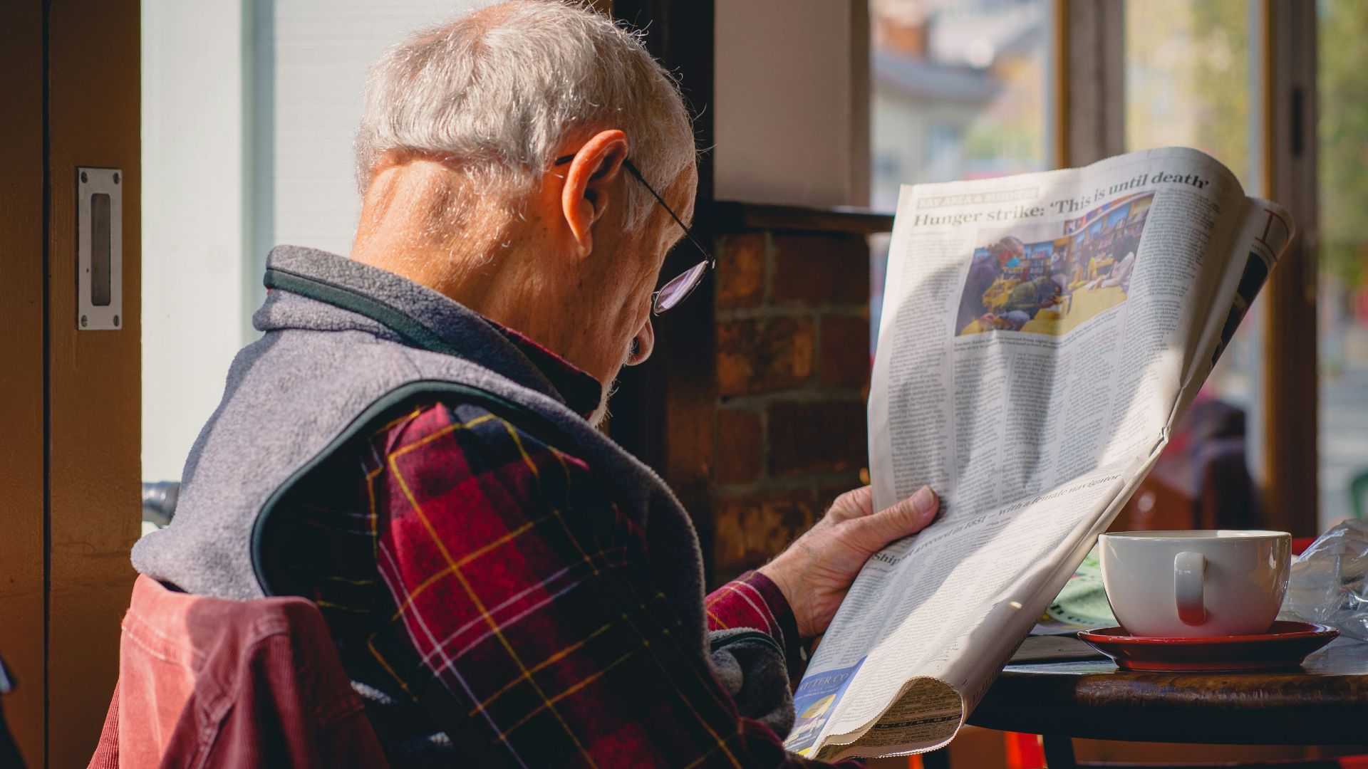 a man sitting at a table reading a newspaper