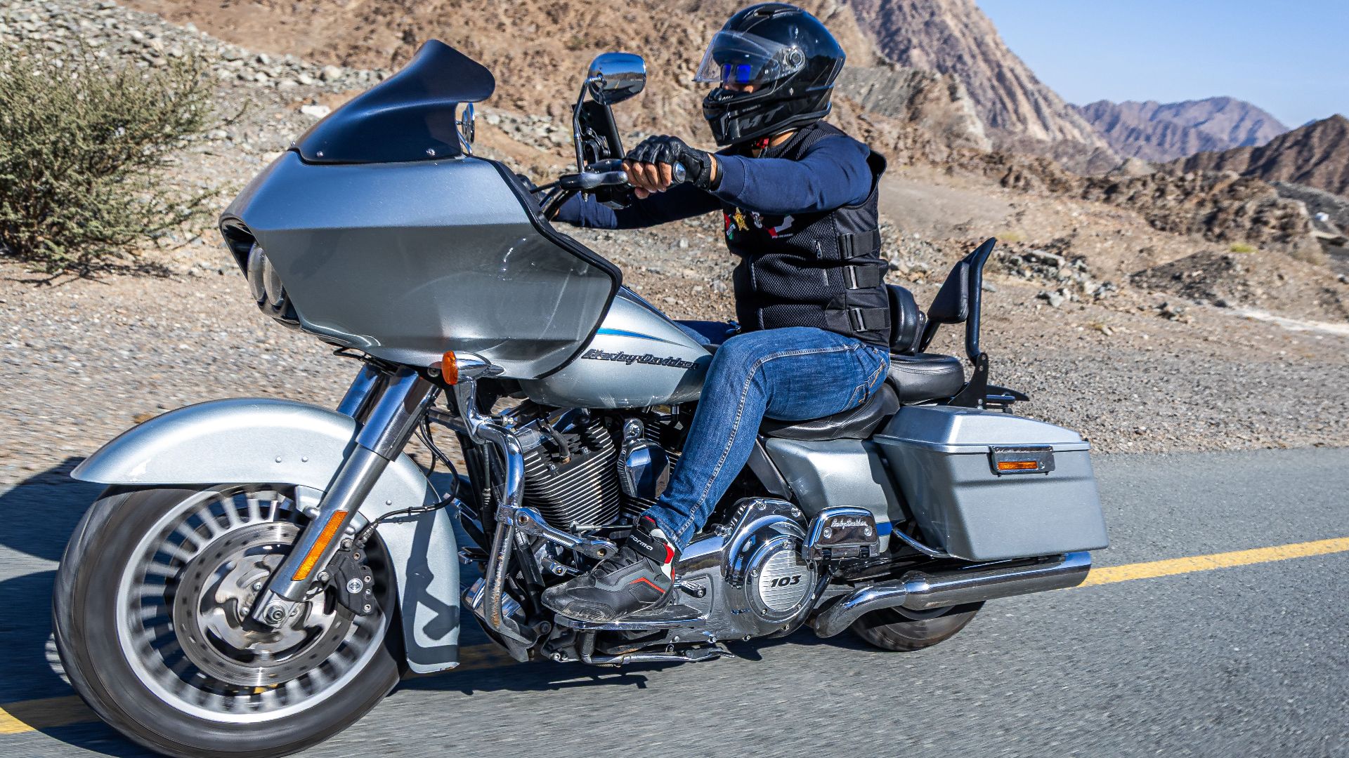 Motorcyclist cruising a Harley-Davidson through scenic Dubai mountains.