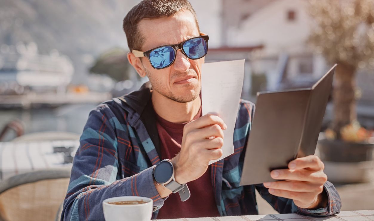 Frustrated Man Examining His Bill at a Coastal Restaurant: Concept of Overcharging Tourists