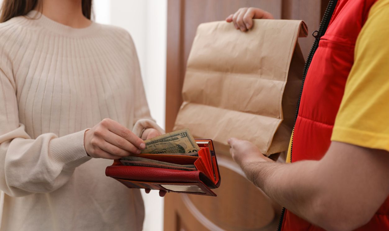 Woman giving tips to deliveryman indoors, closeup