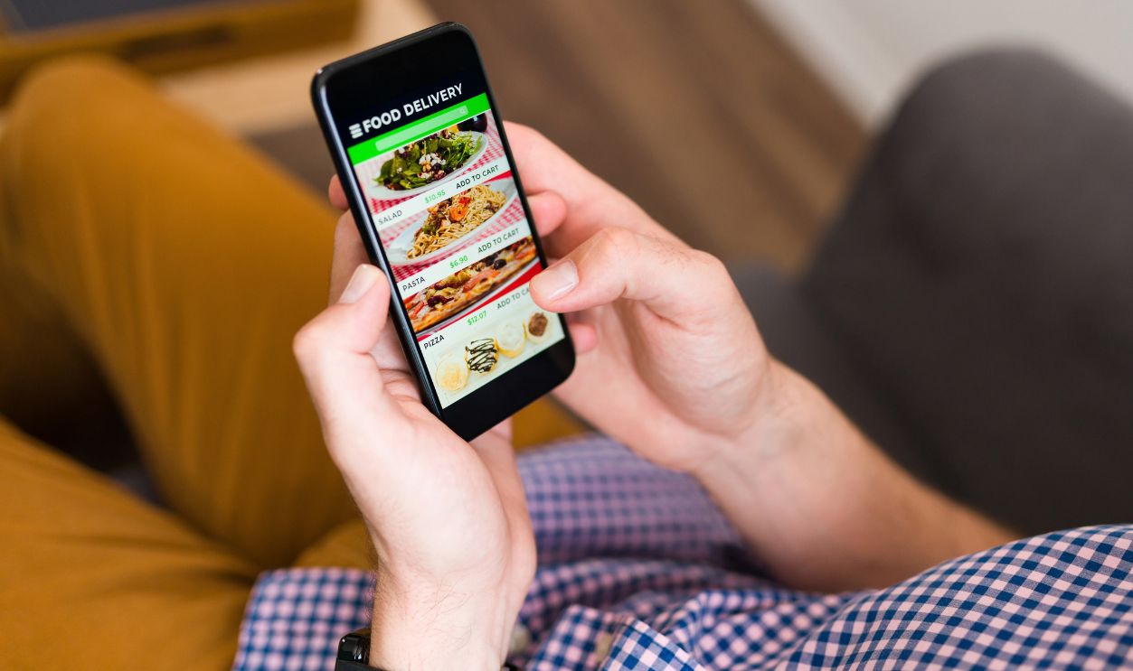 I'm hungry. Hands of a man looking at a food delivery app on his smartphone and ordering dinner online