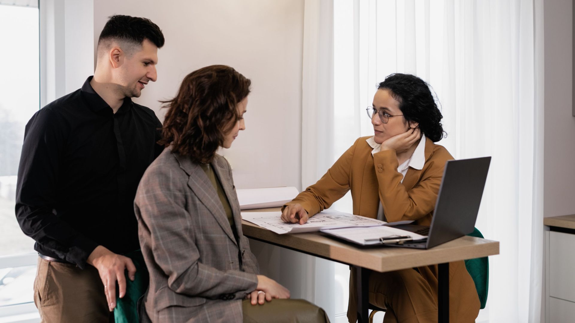 A couple consults a real estate agent in a modern office setting.