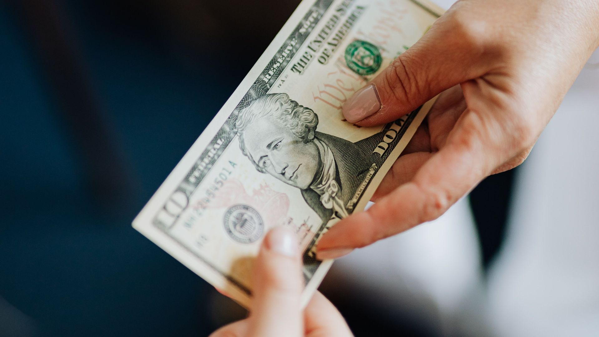 Close-up of hands exchanging a US dollar bill, emphasizing financial transactions.