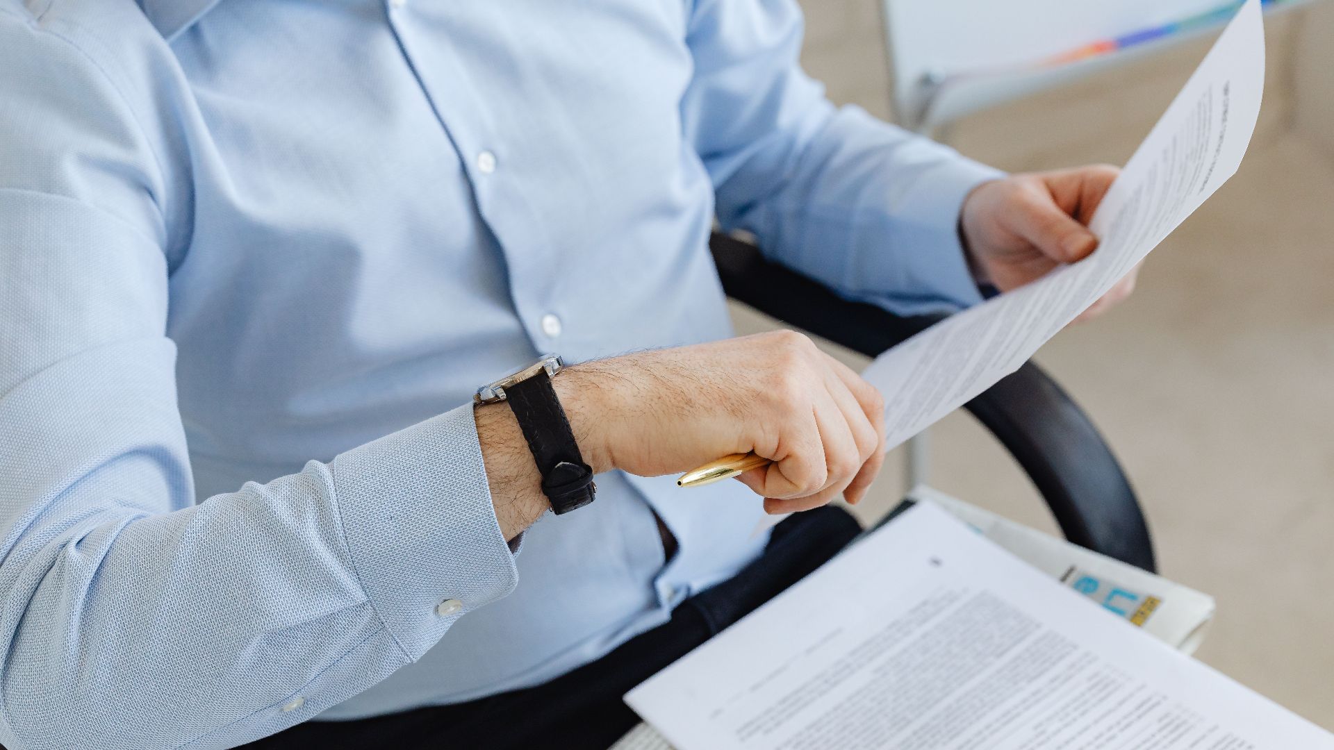 Businessman reviewing papers in office setting, highlighting analysis and attention to detail.