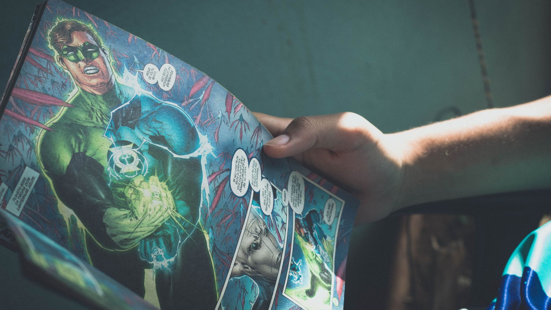 From above of crop anonymous person reading interesting comic book while sitting on chair at home