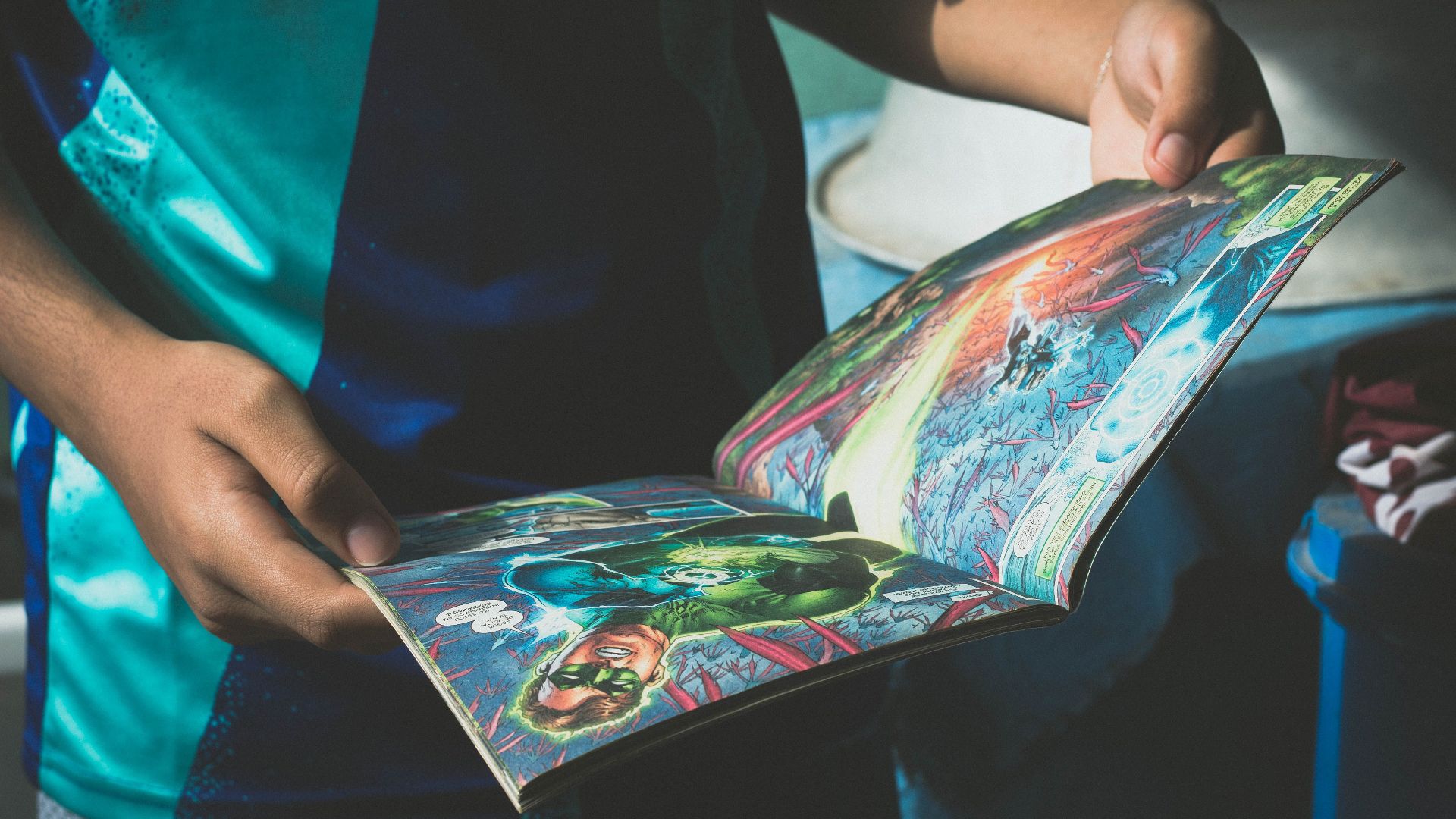 High angle of crop anonymous boy in t shirt reading comic book during weekend at home