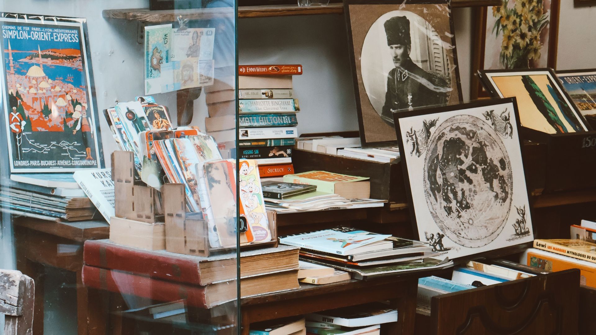 Vintage bookstore window display featuring art, comics, and collectibles.